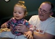 Larry Hill helping his granddaughter bounce on a ball